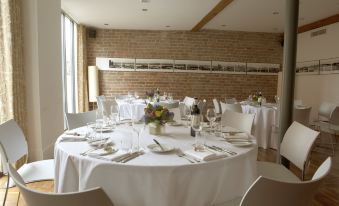 a well - decorated dining room with white tablecloths , chairs , and vases of flowers on the tables at Hope Street Hotel