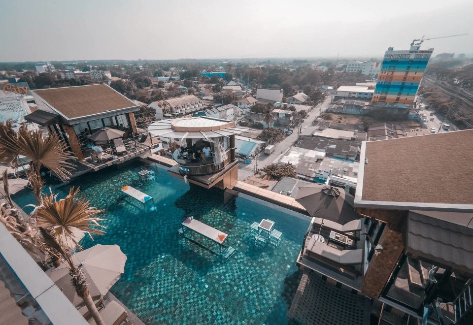 a rooftop pool area with a large pool surrounded by lounge chairs and umbrellas , providing a relaxing atmosphere at ABC Hotel