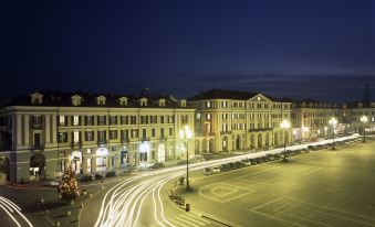 a bustling city street at night , with cars and buildings lit up against the dark sky at Phi Hotel Principe