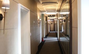 a long hallway with a chandelier hanging from the ceiling and doors on either side at The Riverside Hotel