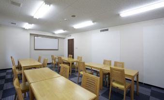 a conference room with wooden tables and chairs , a projector screen , and a whiteboard on the wall at Country Hotel Takayama