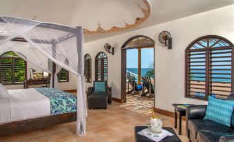 a luxurious bedroom with a canopy bed , a sitting area , and an open door leading to the ocean at Hope House