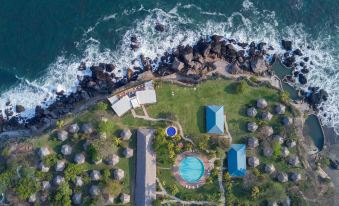 aerial view of a resort on the beach with a pool , umbrellas , and grassy area at Atami Escape Resort