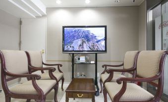 a living room with a flat screen tv mounted on the wall , surrounded by two chairs and a coffee table at Ace Inn Matsumoto