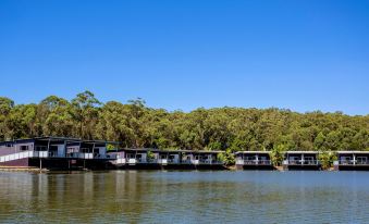 a row of houseboats are docked in a body of water , surrounded by trees and hills at Ingenia Holidays Lake Conjola