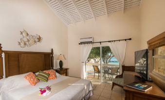 a bedroom with a bed , dresser , and sliding glass door leading to an outdoor area at Bohio Dive Resort