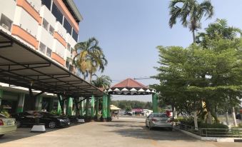 a building with a parking lot and palm trees in front of it , under a clear blue sky at Lopburi Residence Hotel