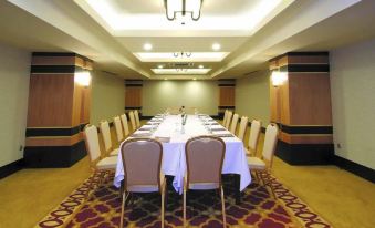 a long table with chairs and a white tablecloth is set up in a large , well - lit room at Dalyan Live Spa Hotel