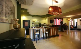 a bar with wooden stools and a green wall , featuring a chandelier hanging from the ceiling at Lantana Garden