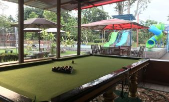 a pool table is set up in a covered outdoor area with umbrellas and slides at Happy Paradise