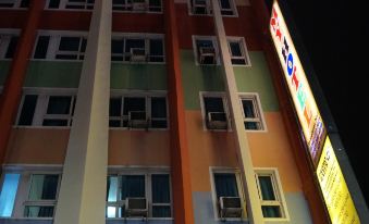 a colorful building with air conditioning units on the side and a neon sign above at My Hotel