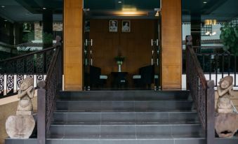 a wooden building with a staircase leading up to the entrance , and a black car parked in front of the building at Diamond Park Inn Chiangrai & Resort