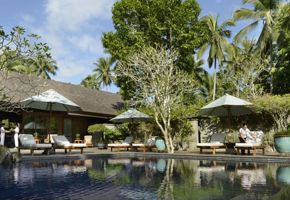 a beautiful outdoor pool area with umbrellas , lounge chairs , and palm trees , under a clear blue sky at The Farm at San Benito