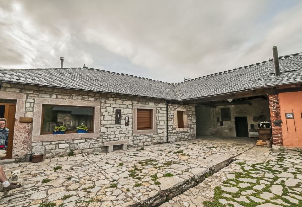 a stone building with a courtyard and a window , surrounded by trees and a cloudy sky at El Lucero
