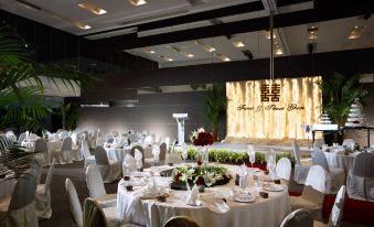 a well - decorated banquet hall with multiple tables set for a formal event , including white tablecloths , chairs , and flowers at Hotel Maya Kuala Lumpur City Centre