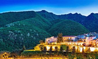 a beautiful mountainous landscape with a large building in the foreground , illuminated by lights at night at Hotel Scapolatiello