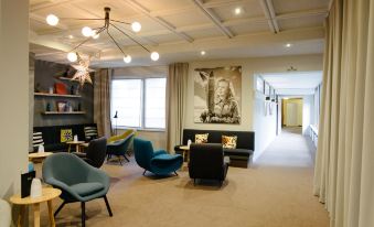 a modern living room with various seating options , including couches , chairs , and a dining table at Hotel Ambassador Zermatt