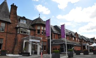 a brick building with purple banners hanging from the roof , possibly indicating a hotel or restaurant at Glynhill Hotel & Spa Near Glasgow Airport