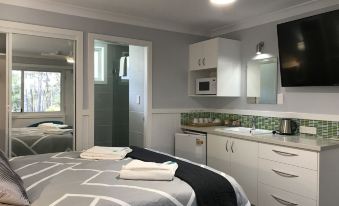 a modern bedroom with a large bed , white cabinets , and a flat - screen tv mounted on the wall at Ulladulla Motel