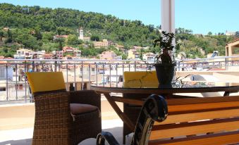 a sunny terrace with wooden furniture , including chairs and tables , overlooking a city and the sea at Dali