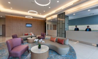 a modern lobby with various seating options , including couches , chairs , and a coffee table , as well as a reception desk at Citadines DPulze Cyberjaya