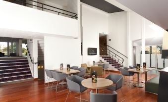 a modern and spacious living room with wooden floors , white walls , and large windows that offer views of the city at Holiday Inn Lille - Ouest Englos