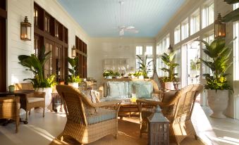 a spacious living room with wicker furniture , including chairs and a couch , arranged around a coffee table at Montage Palmetto Bluff