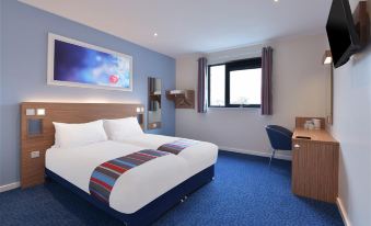 a hotel room with a blue and white bed in the center of the room at Travelodge Sleaford