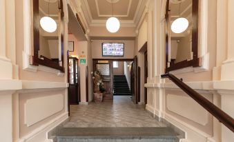 a hallway with a television mounted on the wall and stairs leading up to a doorway at Hotel Victoria