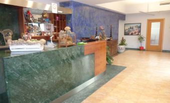 a hotel lobby with a green marble reception desk and a variety of seating options for guests at Hotel Millennium