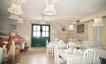 a dining room with a stone wall , white table and chairs , and a green door at Villa Rustica Dalmatia