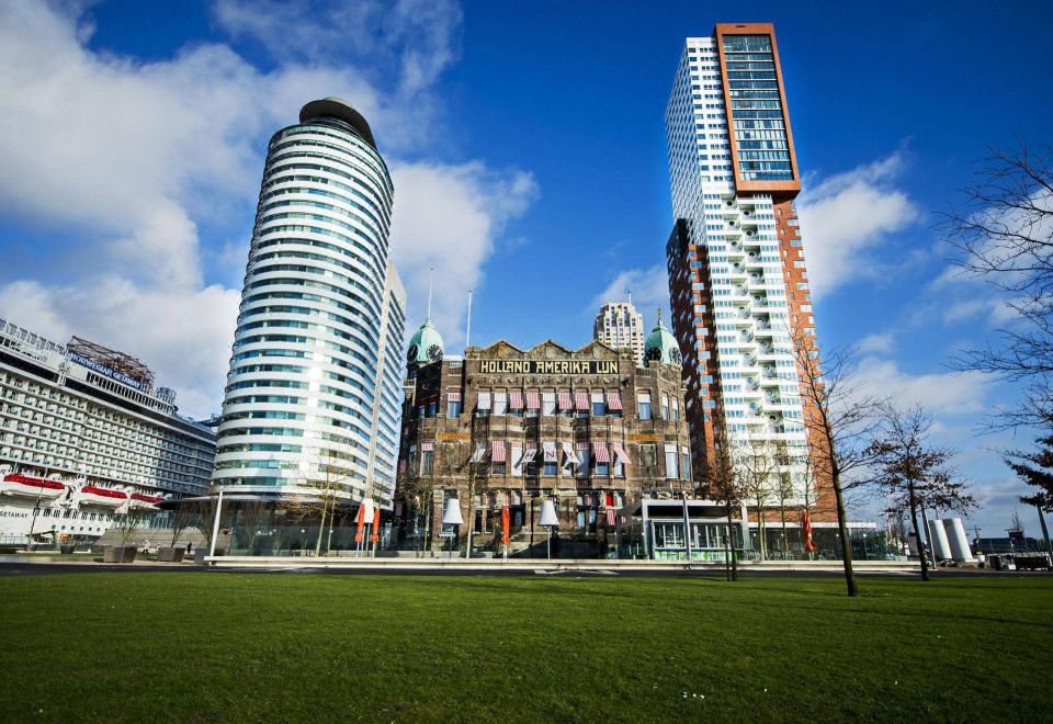 a grassy field with two modern buildings , one on the left and the other on the right , surrounded by trees and a blue sky at Hotel New York