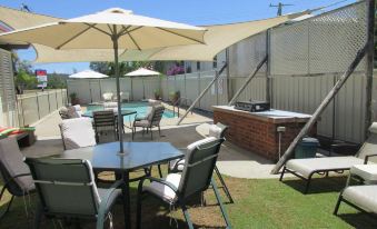 a backyard with a swimming pool surrounded by patio furniture , including chairs and a dining table at Waterview Motel Maclean
