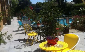 a courtyard with a dining table and chairs set up for outdoor dining , surrounded by lush greenery at Parkwood Motel & Apartments