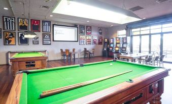a pool table with a white cue stick in the center of a room with chairs and posters on the walls at Nightcap at Wanneroo Tavern