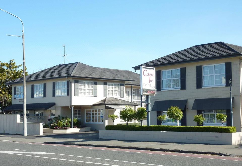 a large house with a sign on the side is located on a street corner at Colonial Inn Motel