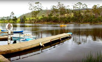 a wooden dock extending into a body of water , with several boats docked at the dock at Gumleaves Bush Holidays
