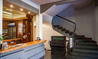 a staircase with a wooden railing leads up to a room with a counter and a window at Hotel Italia