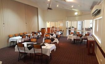 a large dining room with several tables and chairs arranged for a group of people to enjoy a meal together at Emerald Explorers Inn