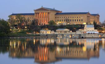 a large building with a clock tower is reflected in the water , and several boats nearby at Sheraton Philadelphia Downtown