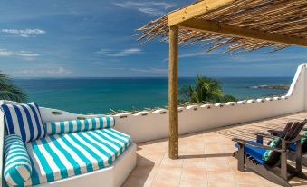 a rooftop patio with a view of the ocean , featuring a blue and white striped bench at Hope House