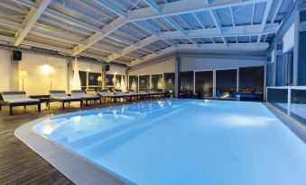 a large swimming pool with a clear blue water and white decking , surrounded by lounge chairs and tables at Hotel Horizon