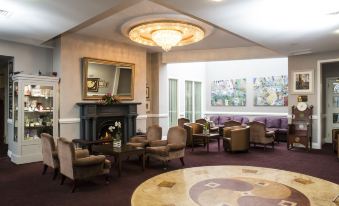 a well - lit living room with comfortable seating , a fireplace , and various artwork on the walls at Brandon House Hotel