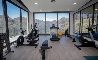 a well - equipped home gym with various exercise equipment , including a treadmill , weights , and an elliptical machine at Eira do Serrado - Hotel & Spa