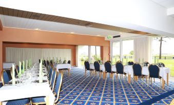 a large , empty conference room with blue carpet and white tables set up for an event at Hotel Marina