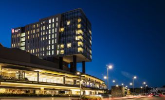 a modern building with large windows and a glass facade is lit up at night at Fiesta Inn Express Queretaro Constituyentes