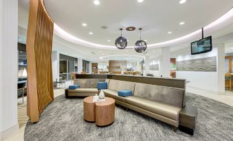 a modern and clean lobby area with couches , chairs , and tables arranged in a seating area at SpringHill Suites Houston the Woodlands