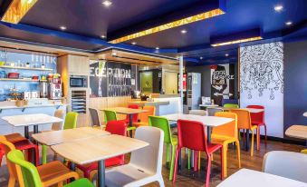 a brightly colored dining room with tables and chairs arranged in various positions , creating a welcoming atmosphere at Ibis Budget Windsor Brisbane