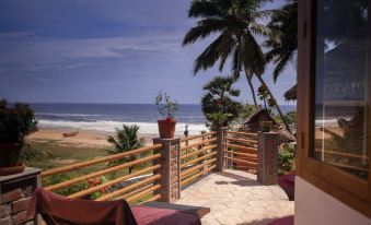 a wooden deck with chairs and a view of the ocean , surrounded by palm trees at Somatheeram Ayurveda Village