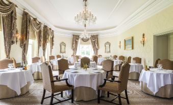 a large , elegant dining room with multiple tables and chairs arranged for a formal event at Lucknam Park Hotel